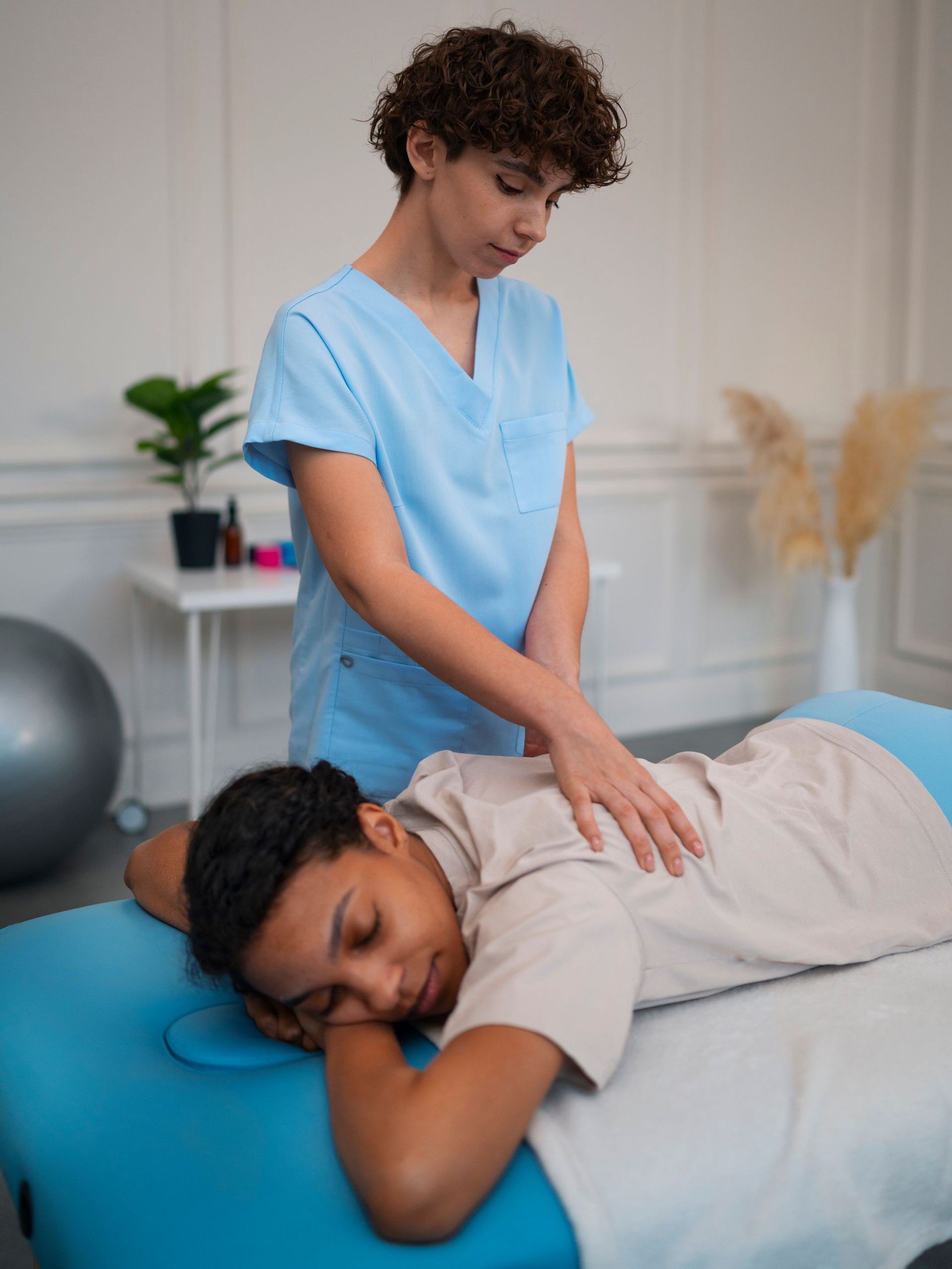 Therapist giving a back massage to a client on a treatment table in a clinic room