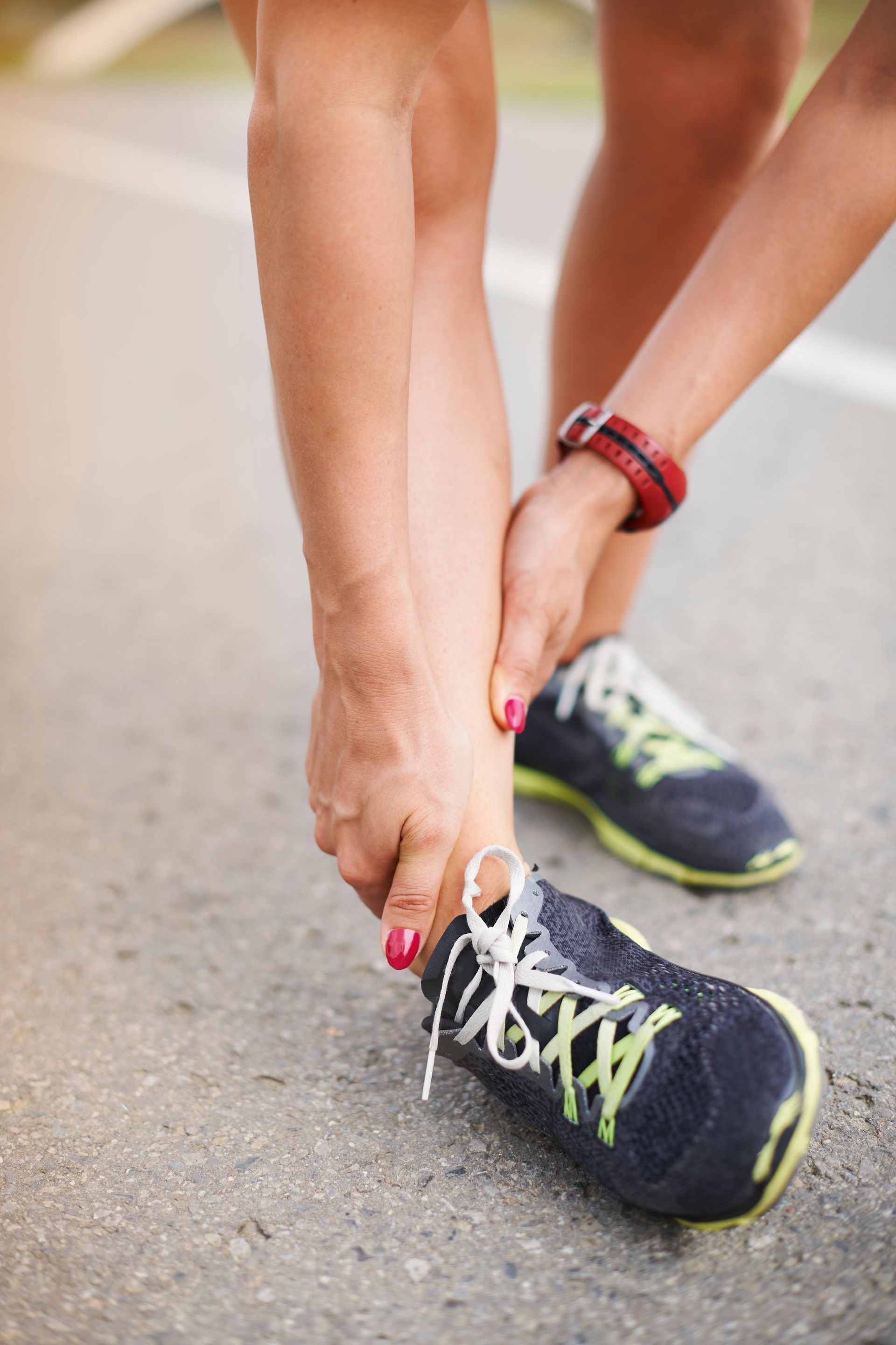 A woman is tying her shoes on the side of the road.