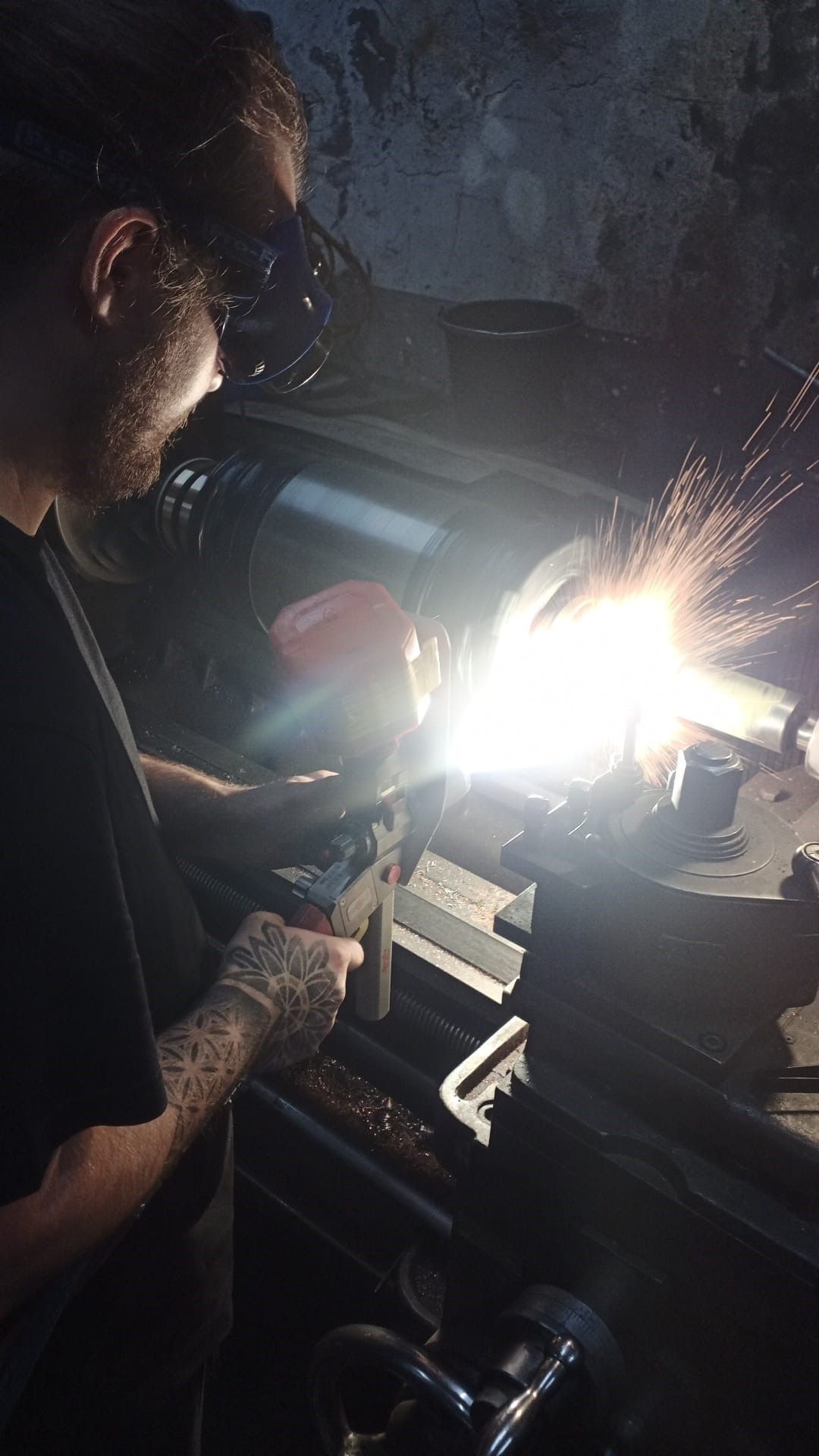 Ein Mann schweißt in einem dunklen Raum ein Stück Metall.