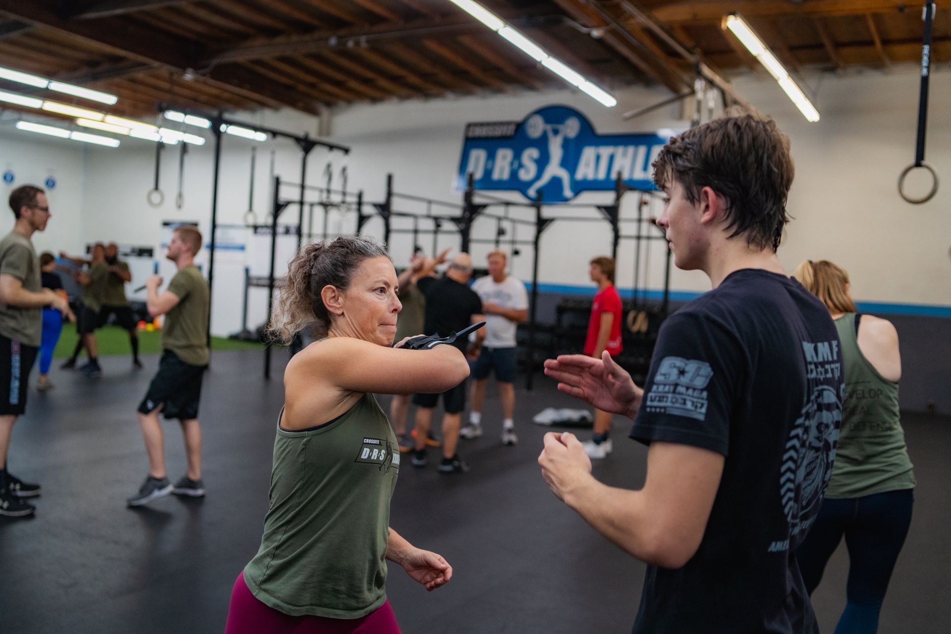 A group of people are standing in a gym talking to each other.