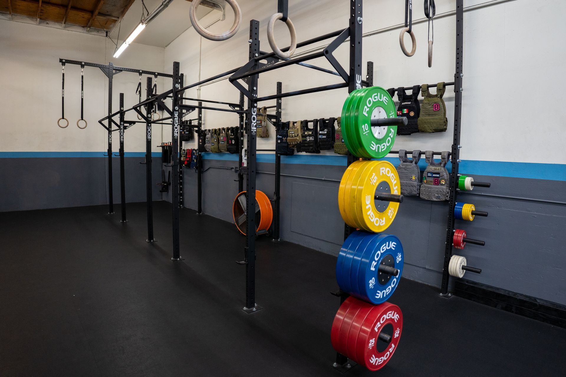 A gym with a lot of weights and rings on the wall.