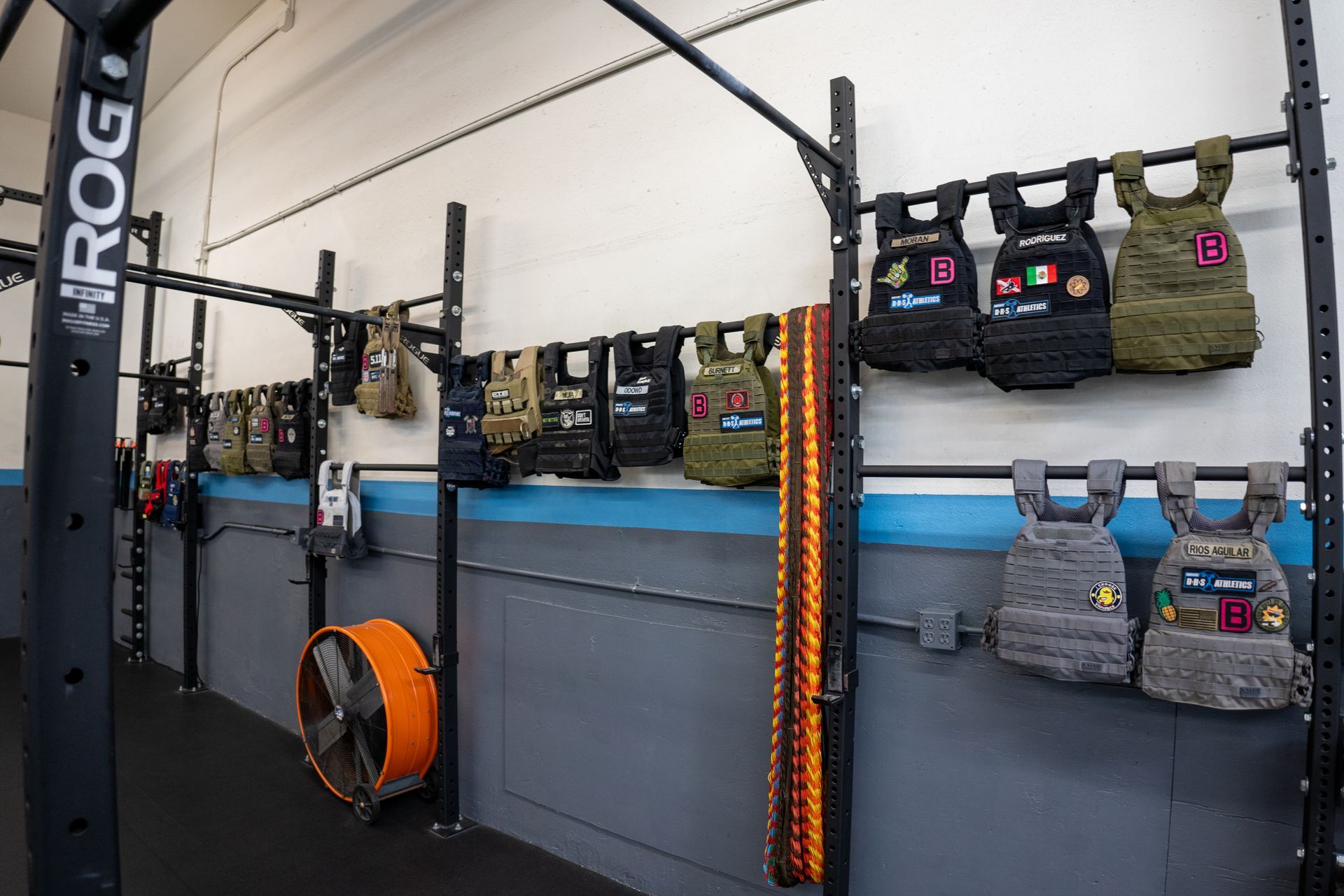 A row of weight vests hanging on a rack in a gym.