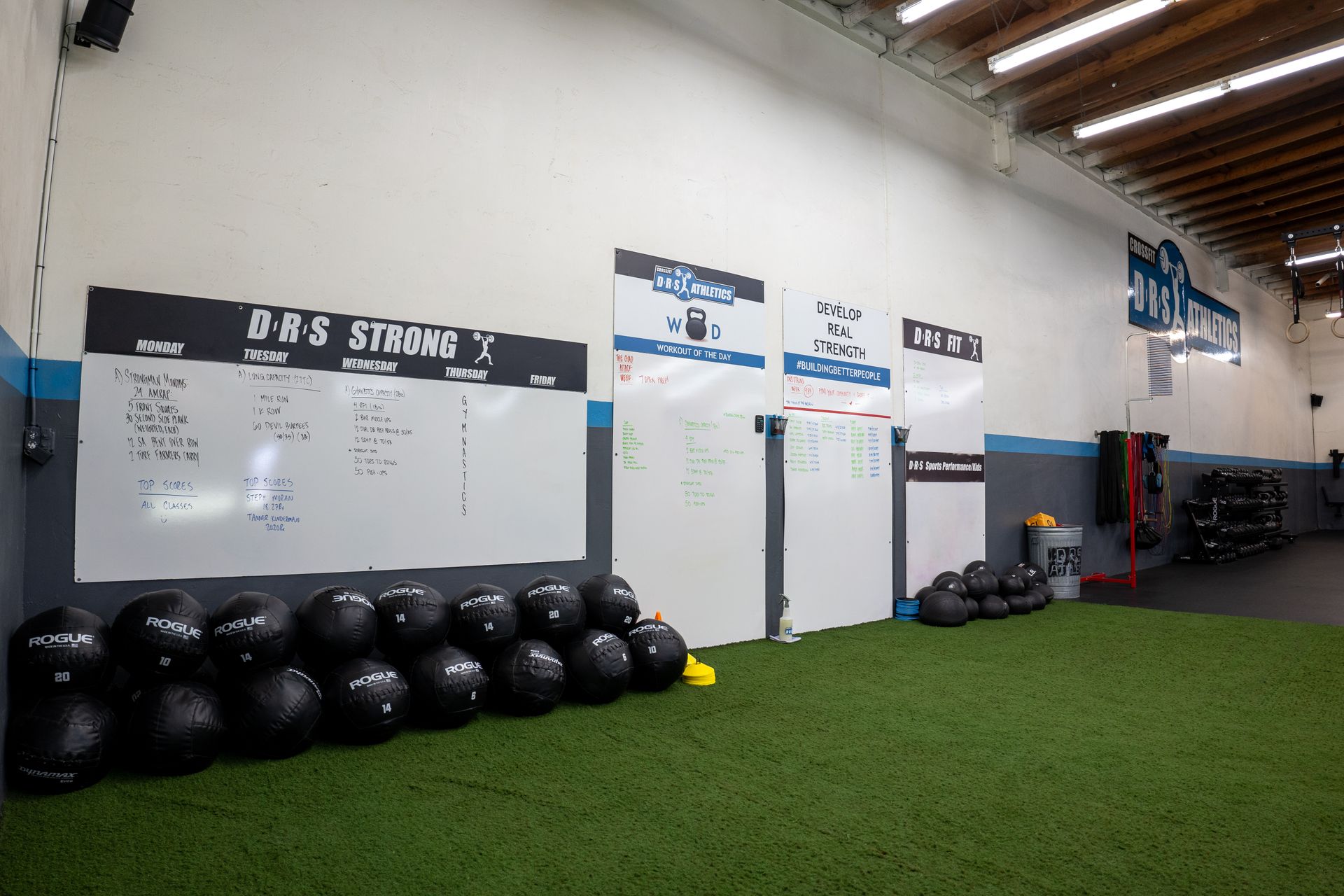 A gym with a bunch of balls and a white board on the wall.