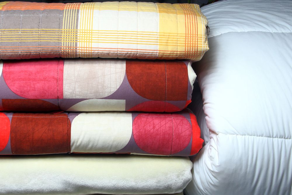 A Pile of Blankets and Pillows Stacked on Top of Each Other on a Bed — The Comfort Zone Darwin In Winnellie, NT