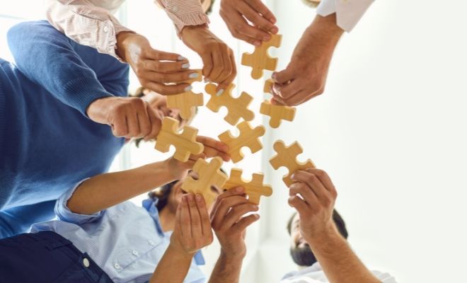 A group of people are putting puzzle pieces together in a circle.