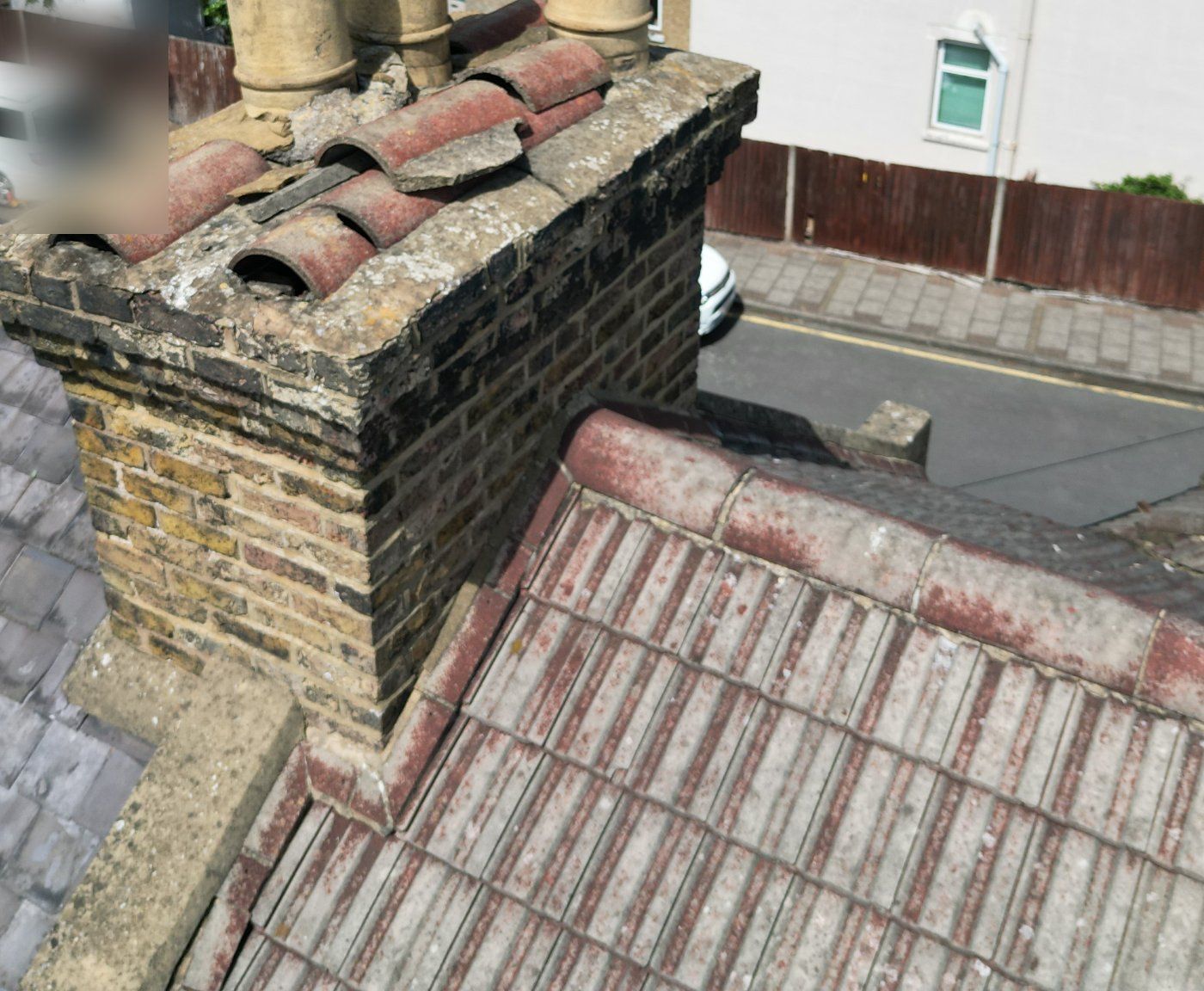 Shared chimney stack on the party wall between two roofs, slate on one side and concrete tiles on the other