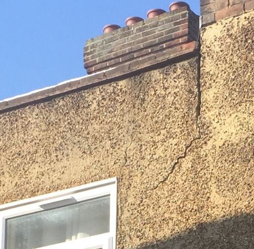 Diagonal crack in rendered wall below a chimney stack, recorded during a structural inspection