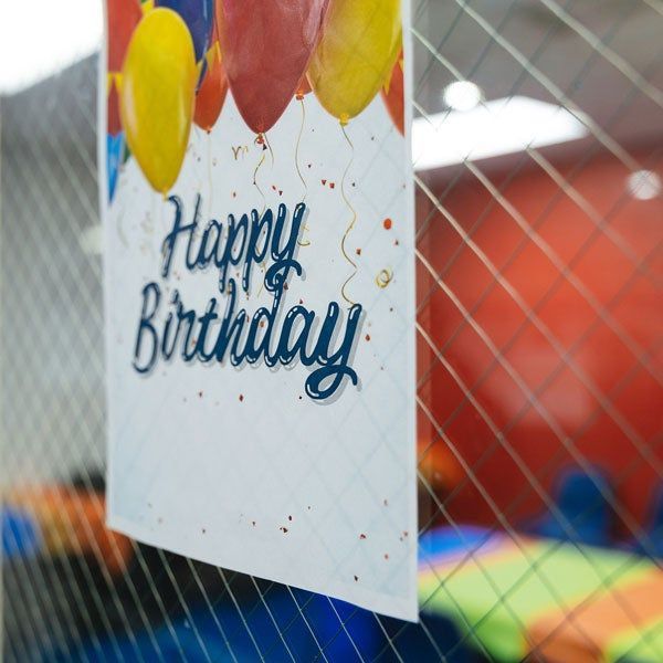 Happy Birthday sign with balloons hanging in a colorful indoor play area