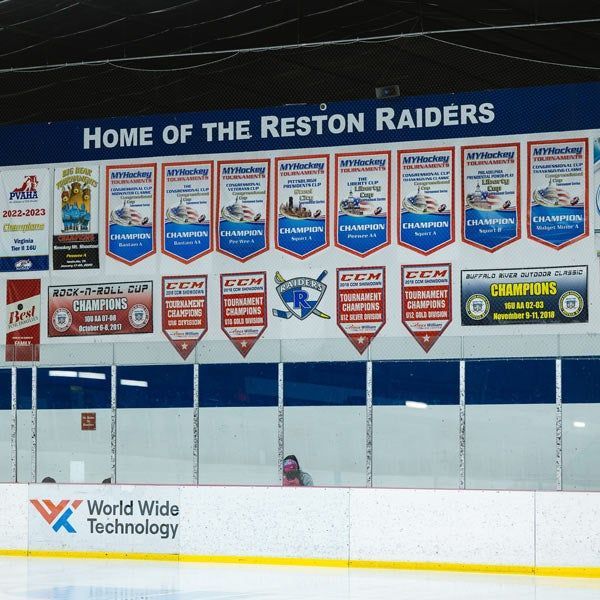 Wall of championship banners in a hockey rink labeled “Home of the Reston Raiders”