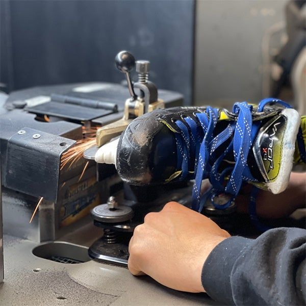 worker sharpening blades on hockey skates