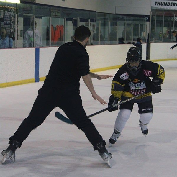 Two hockey players battling for the puck on an ice rink, one in black and one in black/yellow.