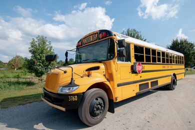 Yellow school bus on a rural road under a blue sky