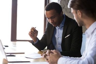 Two coworkers discussing documents at a bright office table