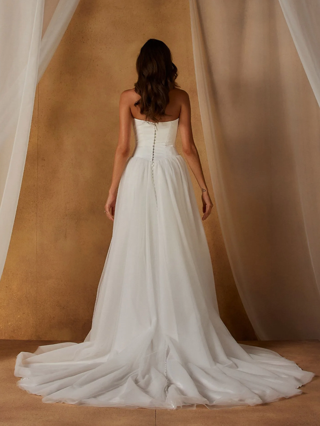 Our Nordic wedding dress exists in the space between modern and whimsical. Blending the two styles seamlessly for a look that feels both romantic and fashionable in the most effortless way.
The clean, velvet satin bodice begins at a contemporary scoop neckline. With the option to be worn strapless or with spaghetti straps for added support. Curved seamlines create shape throughout the bodice, ending at the sharp Basque waist that cinches the figure.