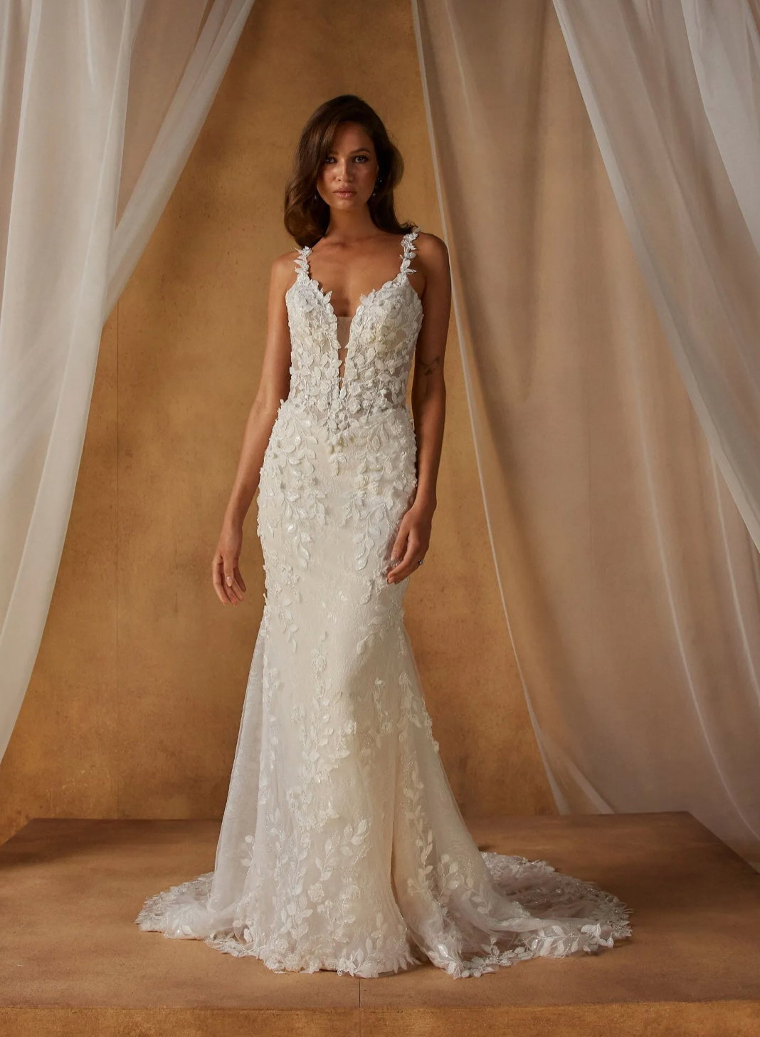 Nita  van Madi Lane heeft een trompet silhouet met een laag glitter tule om een ​​extra glans toe te voegen aan haar all-over pailletten kantpatroon. Haar lijfje is ontworpen met een moderne, trendy piek-stijl halslijn met een sexy maar ingetogen illusie plunge. 