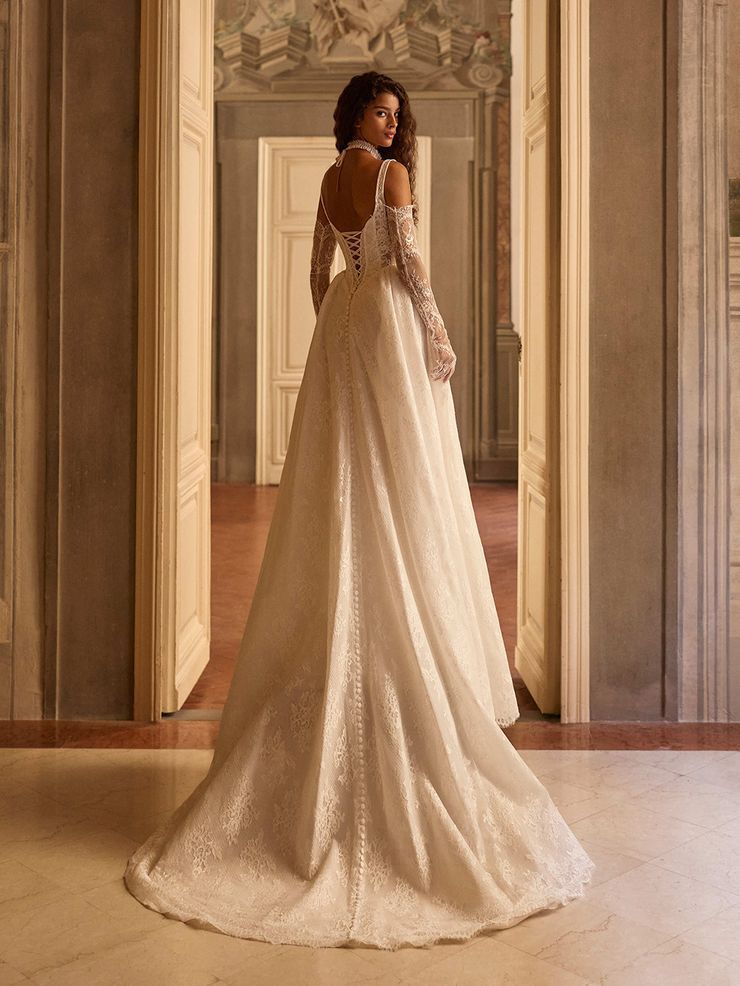 Chantilly lace A-line gown featuring a cupless corset bodice with a square neckline and delicate straps. The full, sweeping skirt is finished with chantilly lace-covered decorative buttons, creating a refined and timeless silhouette.
Pairs beautifully with the Arlisse or Iverly choker and Odyssia gloves, landing the look on its final, romantic 
