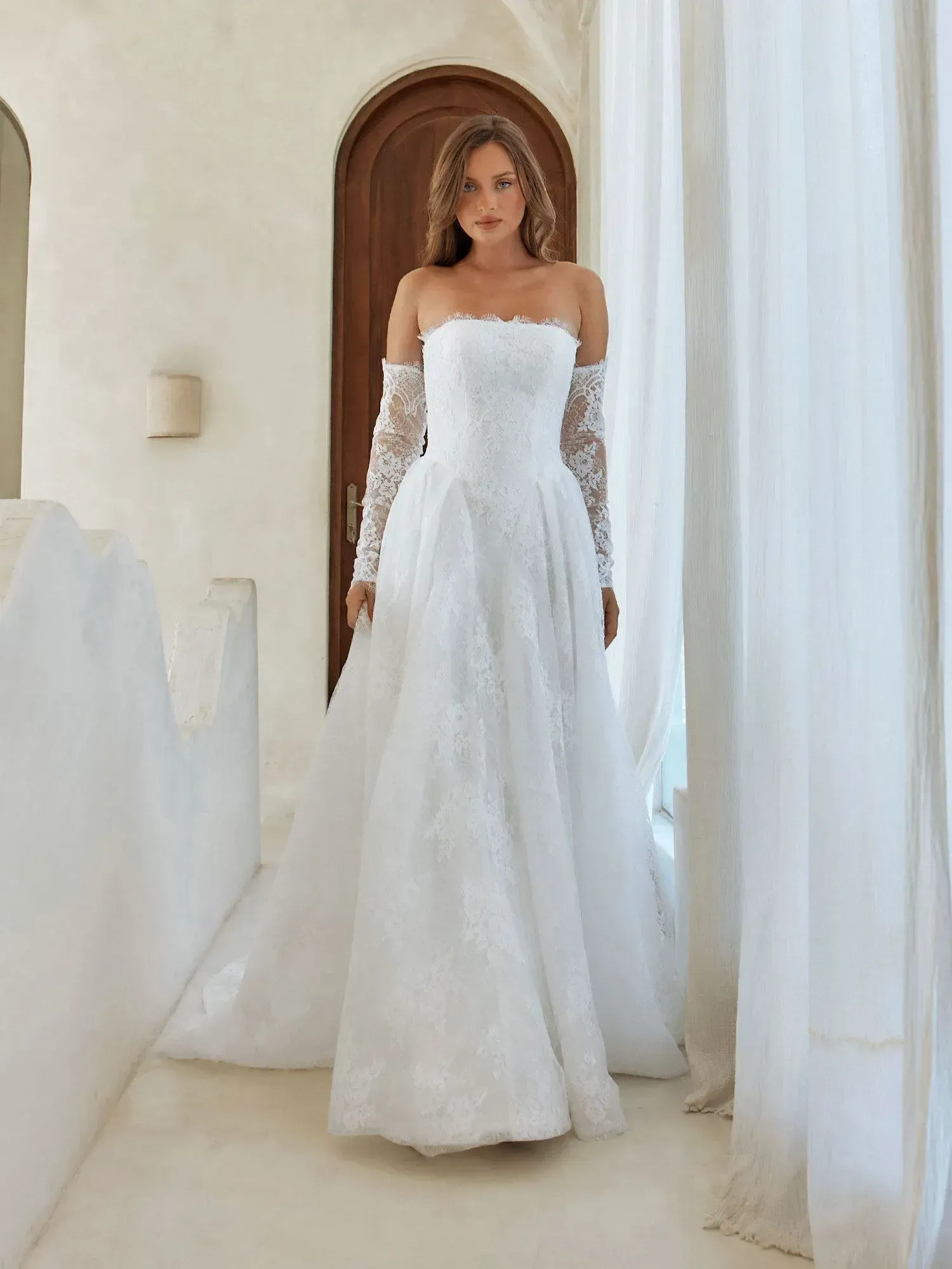 Nita  van Madi Lane heeft een trompet silhouet met een laag glitter tule om een ​​extra glans toe te voegen aan haar all-over pailletten kantpatroon. Haar lijfje is ontworpen met een moderne, trendy piek-stijl halslijn met een sexy maar ingetogen illusie plunge. 