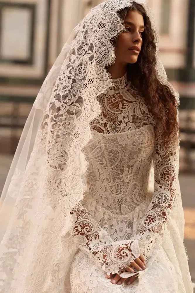 Romantic princess lace gown with a sleeveless corset bodice and a full princess skirt. Comes with a high-neck long-sleeved lace bolero that allows you to switch between two different looks on your big day.
For a completely dreamy ensemble, finish off with a lace-adorned Almarose tulle veil.