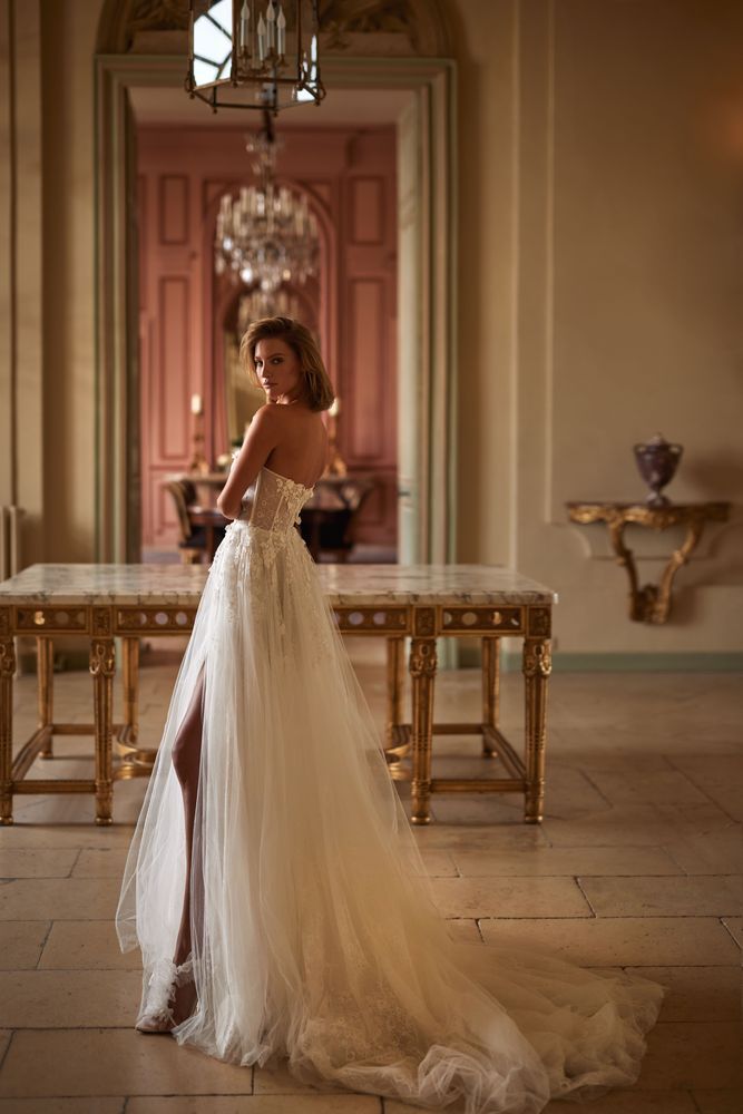Magnificent A-line semi-transparent wedding gown crafted from chantilly lace, delicately sprinkled with 3D flowers and sequins. Boasting a heart-shaped semi-transparent corset with built-in cups, adorned with 3D floral appliqués and sequins, a zip closure on the back, and a voluminous tulle skirt over chantilly lace.
Can be complemented with a bolero Calvin.