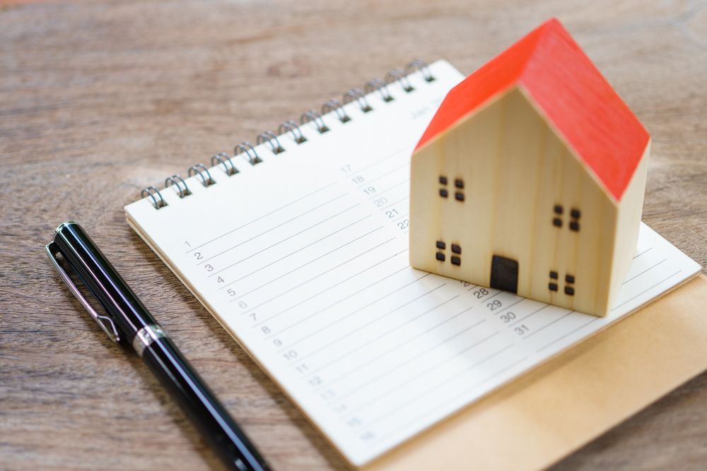 a model house is sitting on top of a notebook next to a pen