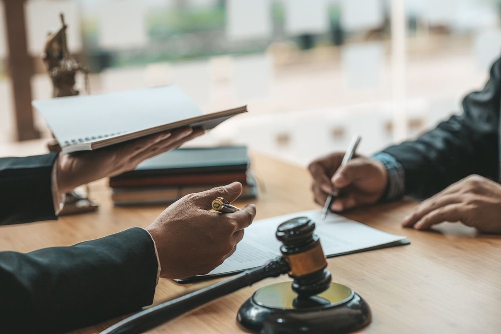 a judge is holding a clipboard and a gavel while a man signs a document