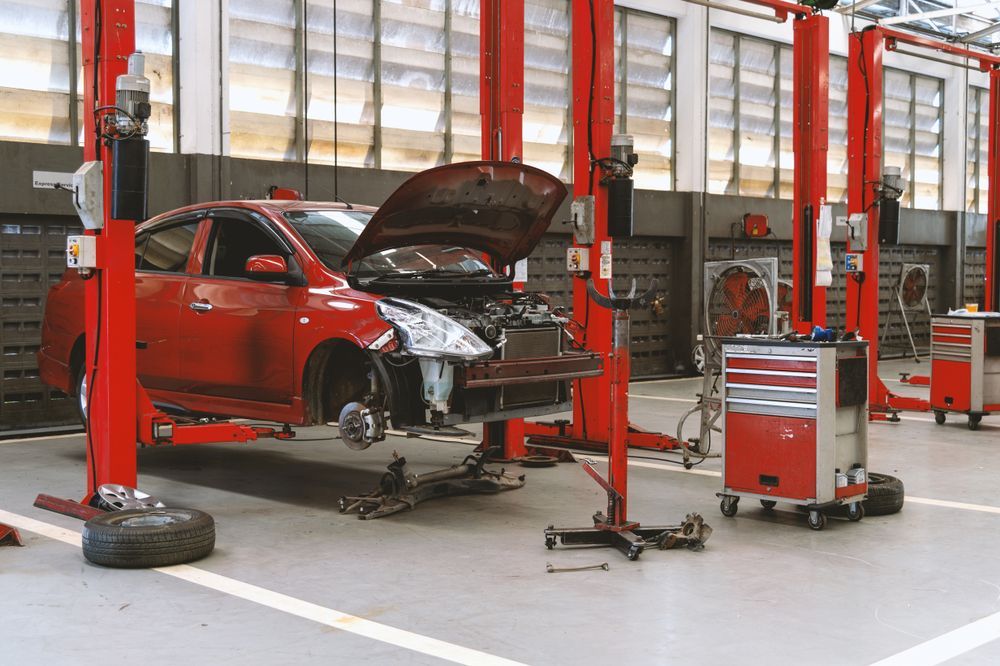 Red Car Raised on a Lift in a Repair Shop, Hood Open, Tools Nearby — Supalook Smash Repairs In Port Macquarie, NSW