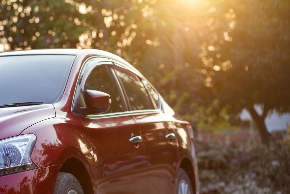 Red Sedan Car Parked, Sunlight Shining Through Trees in the Background — Supalook Smash Repairs In Port Macquarie, NSW