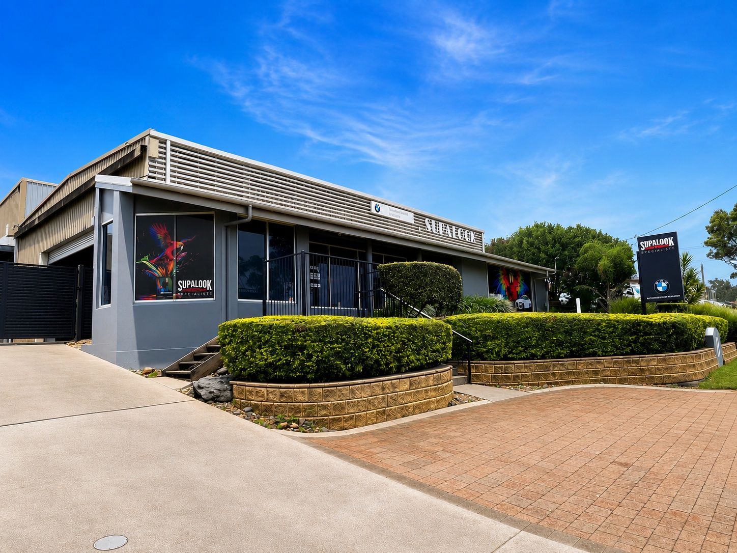 Modern storefront with grey facade, hedges, and blue sky on a sunny day — Supalook Smash Repairs In Port Macquarie, NSW