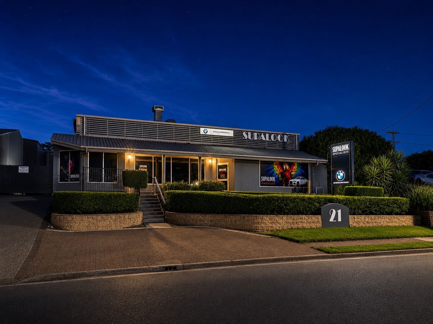 Modern restaurant exterior at dusk with lit windows, blue sky — Supalook Smash Repairs In Port Macquarie, NSW