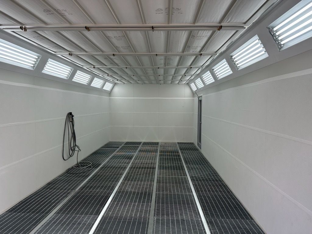 Empty white industrial room with grated floor, ceiling vents, and a coiled hose on the wall — Supalook Smash Repairs In Port Macquarie, NSW