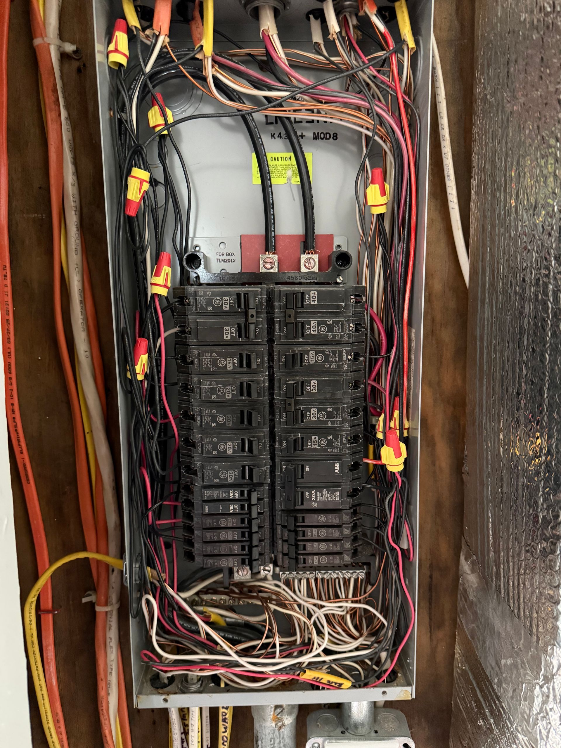 Person using a multimeter to test electrical wiring in a panel.