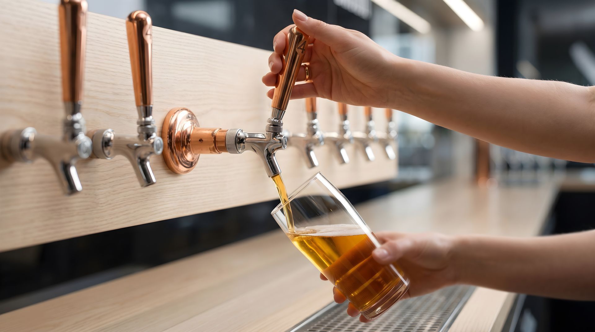 Hand filling a beer mug from a row of beer taps at a bar counter