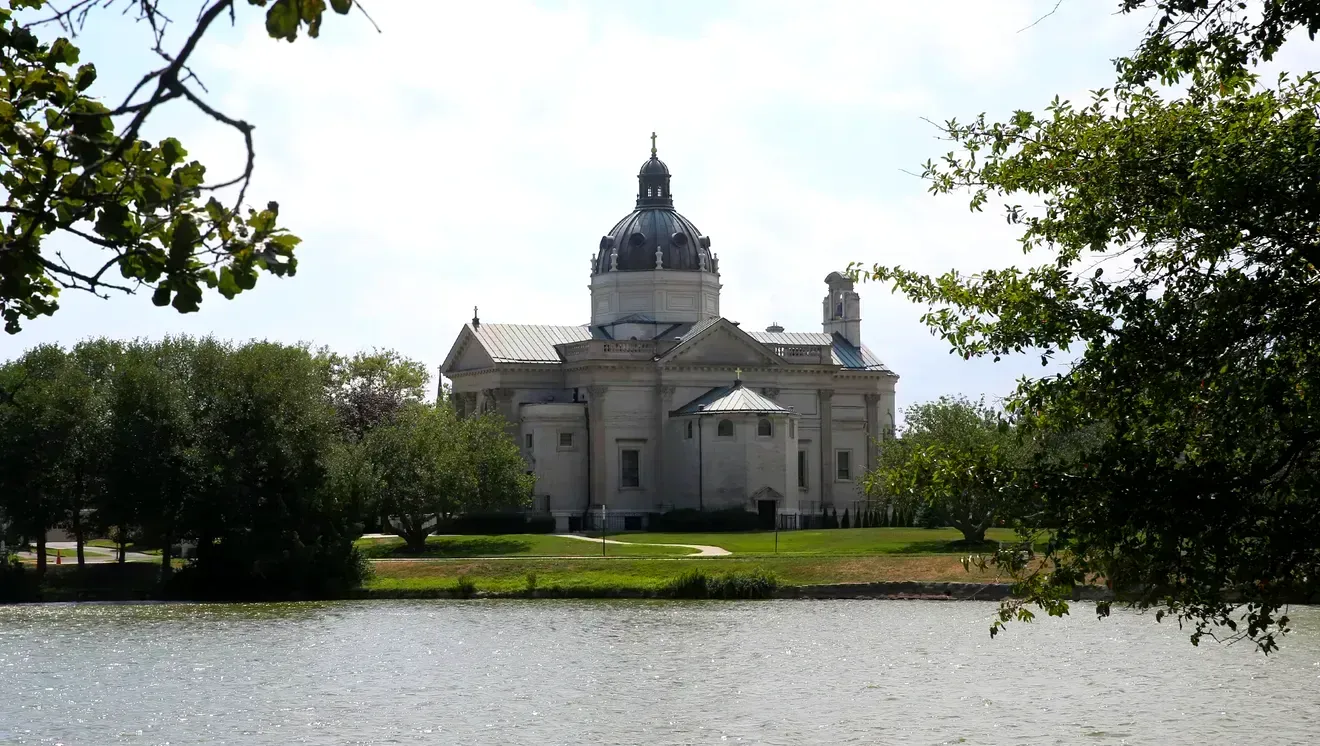 A large building is surrounded by trees and a body of water