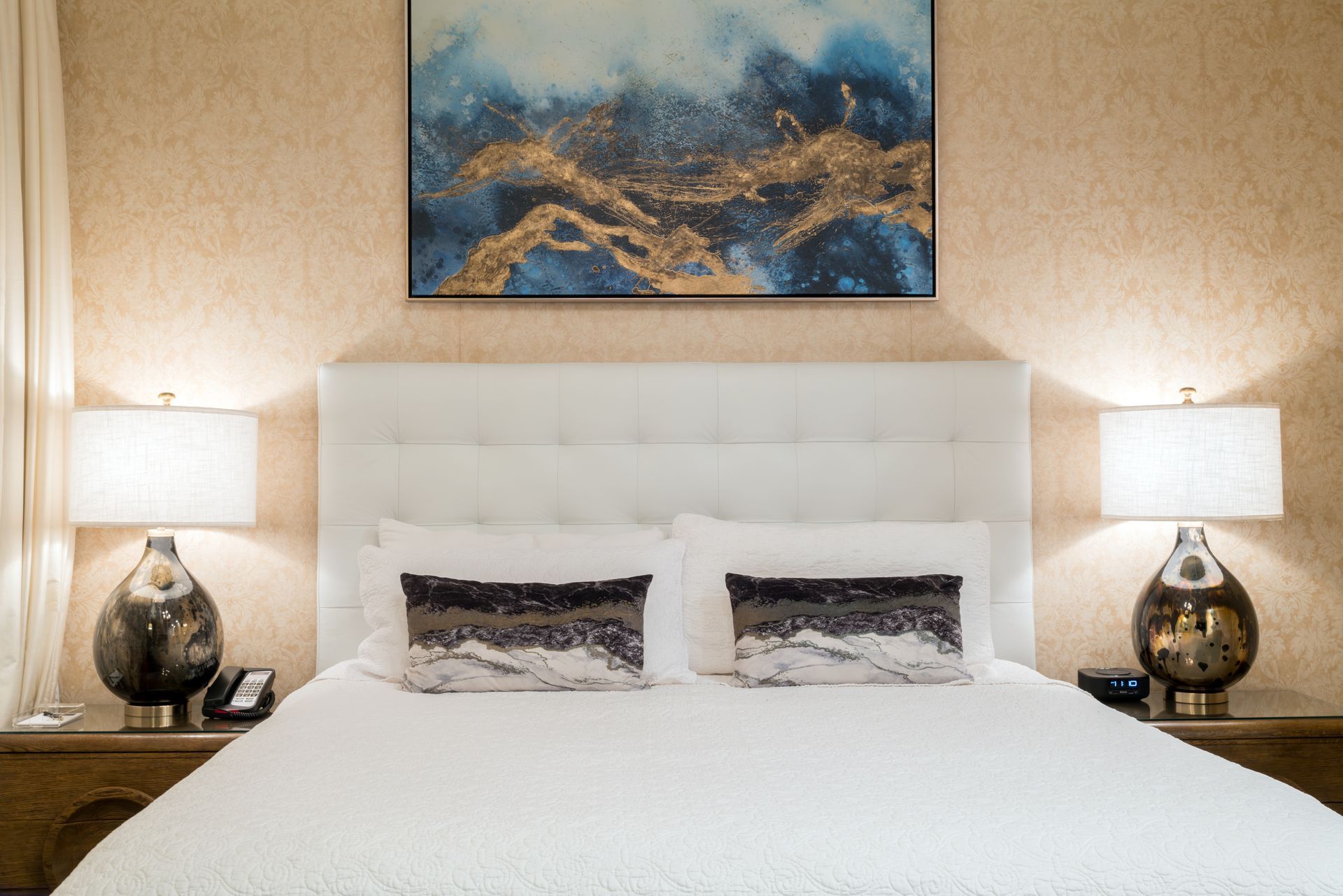 There is a painting on the wall above the bed.