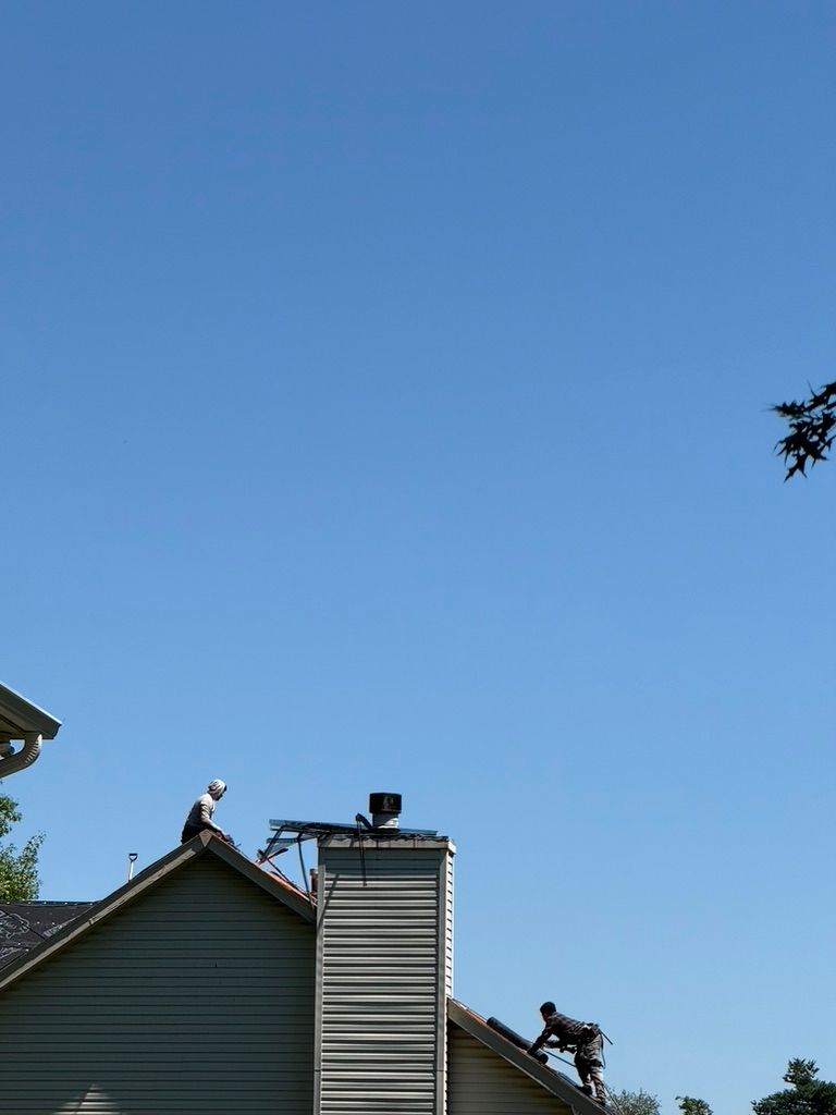 Workers on a rooftop repairing a house under a clear blue sky