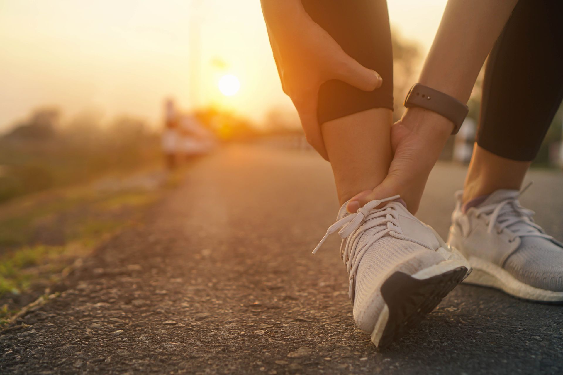 Person on path, holding ankle in pain; sunrise in background.