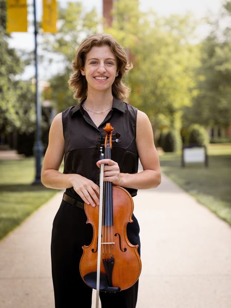 Headshot of Millie Meunier holding her viola and smiling into the camera.