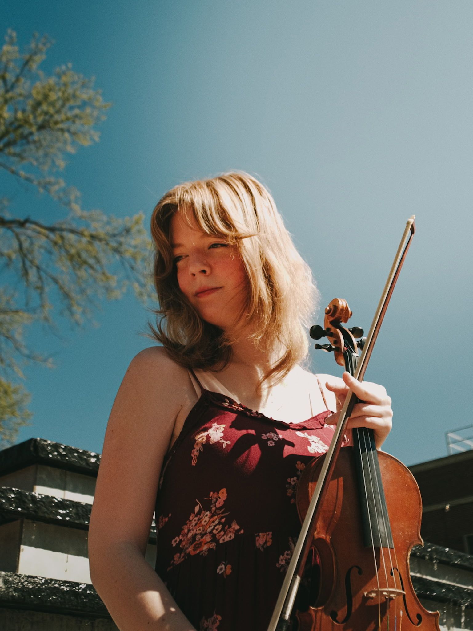 Headshot of Audrey Cox holding her violin and looking off into the distance.