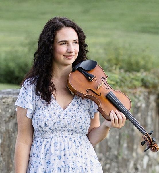 Headshot of Anna Touchstone holding her violin and looking off into the distance.