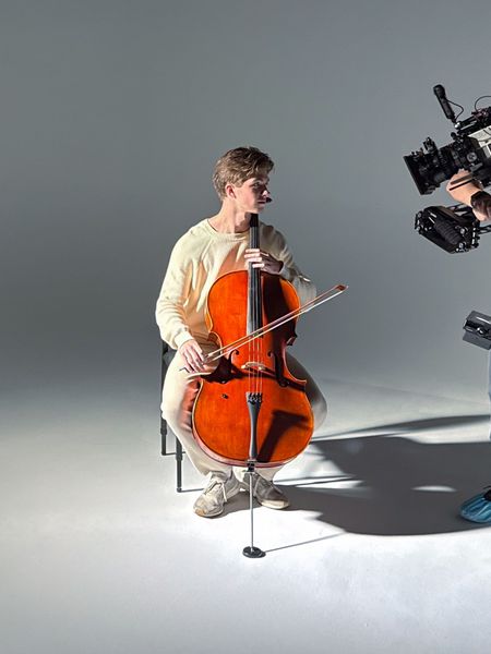 Brendan Novak holding his cello posing for a music video shoot.