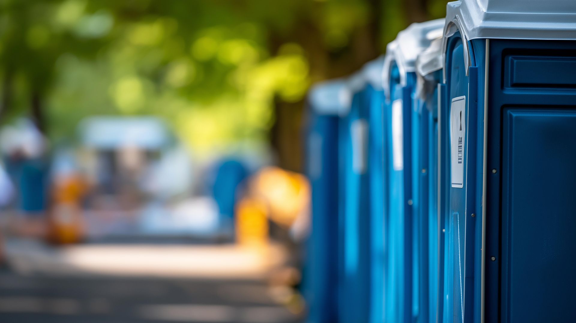 Row of blue portable toilets at an outdoor event site.
