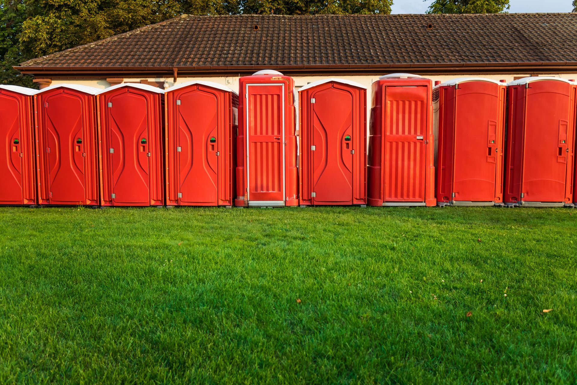 Portable plastic red toilets in a park.
