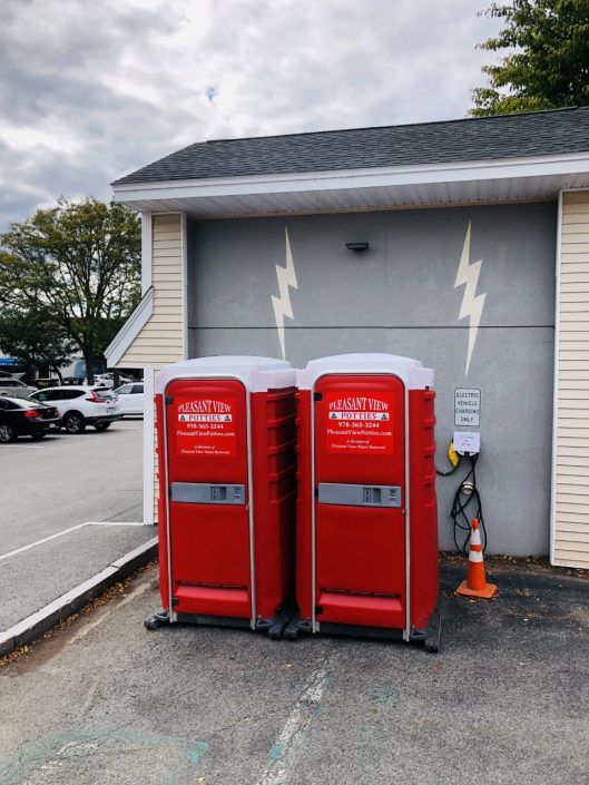 A row of blue portable toilets are lined up on the grass.