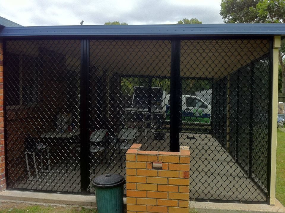 A Screened In Area With A Brick Wall And A Green Trash Can — Affordable Screens & Blinds in Thabeban, QLD