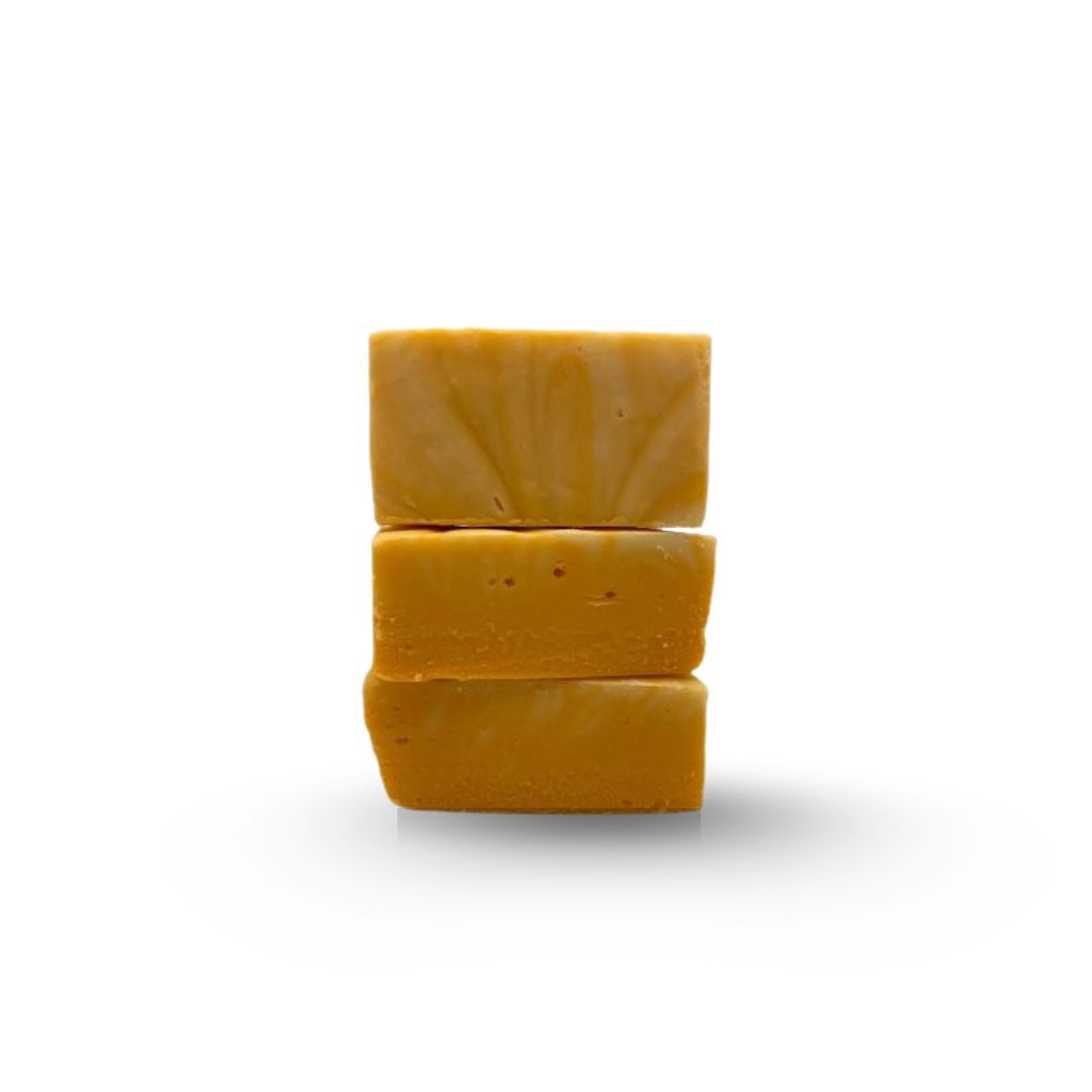 Three stacked, square, golden-yellow bars, possibly soap, against a white background.