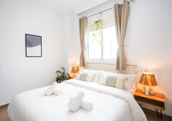 Un dormitorio con una cama, dos lámparas y una ventana.