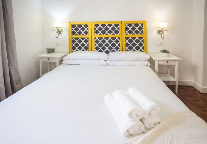 Un dormitorio con una cama y un cabecero amarillo.