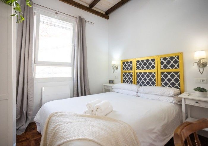Un dormitorio con cama, mesita de noche y ventana.