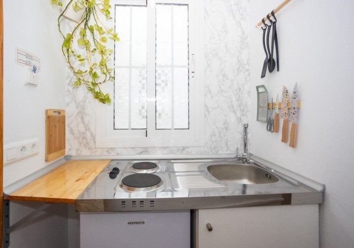 Una pequeña cocina con fregadero, estufa y ventana.