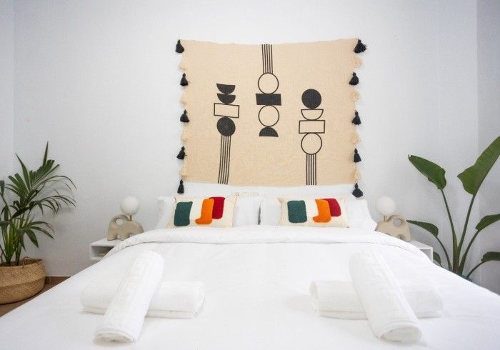 Una cama con un tapiz en la pared encima.